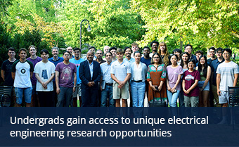 A large group of electrical engineering students and faculty pose outdoors on a brick walkway